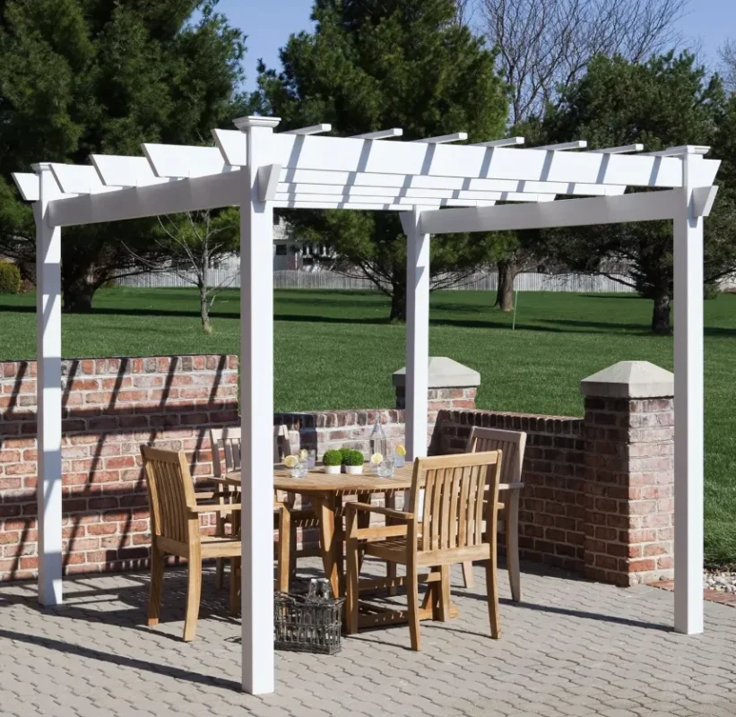 Dura-Trel Kingston 7 x 7 ft white vinyl pergola over a round teak dining table on a brick-walled patio